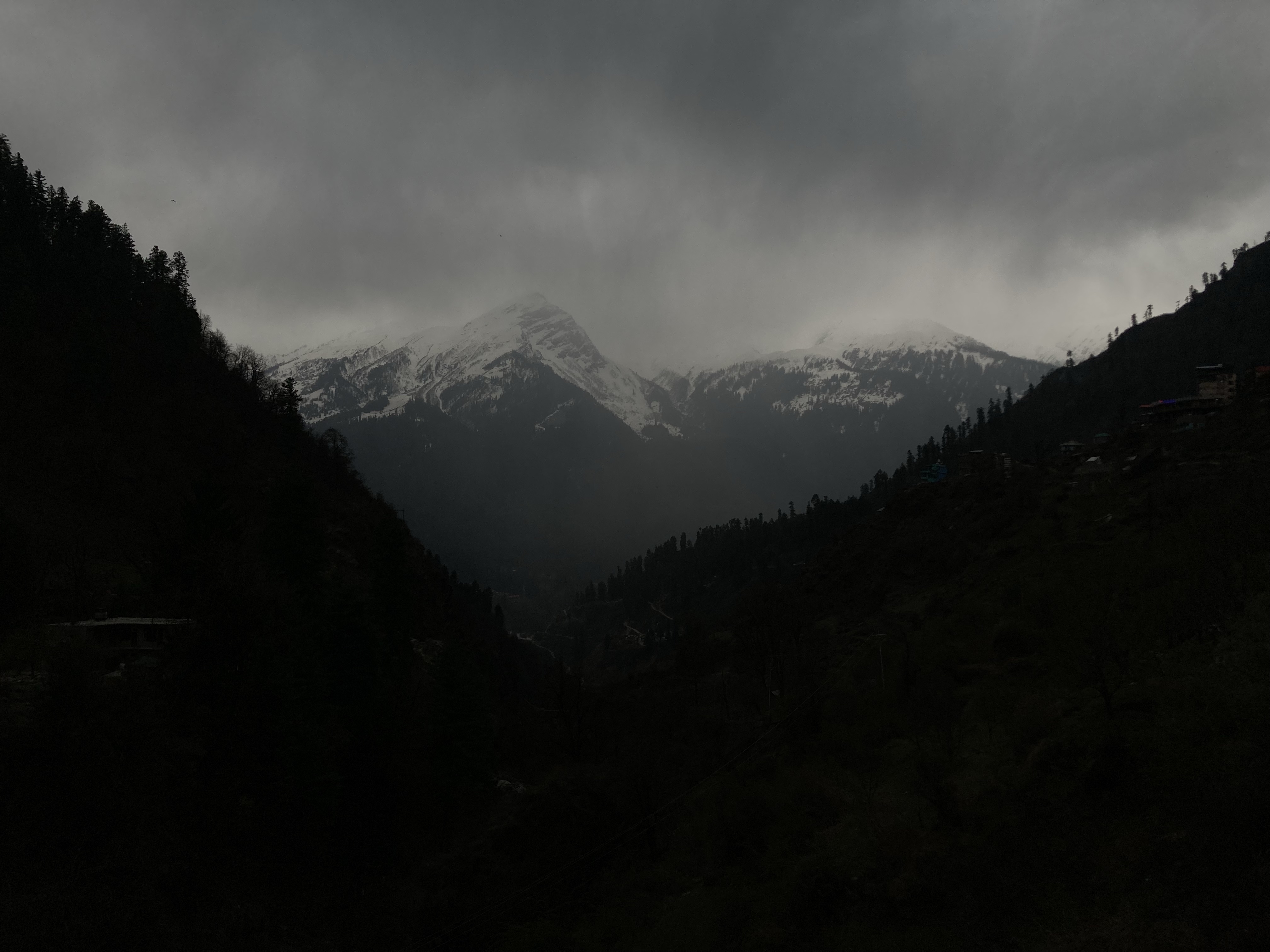 A dark mountain valley under a cloudy sky