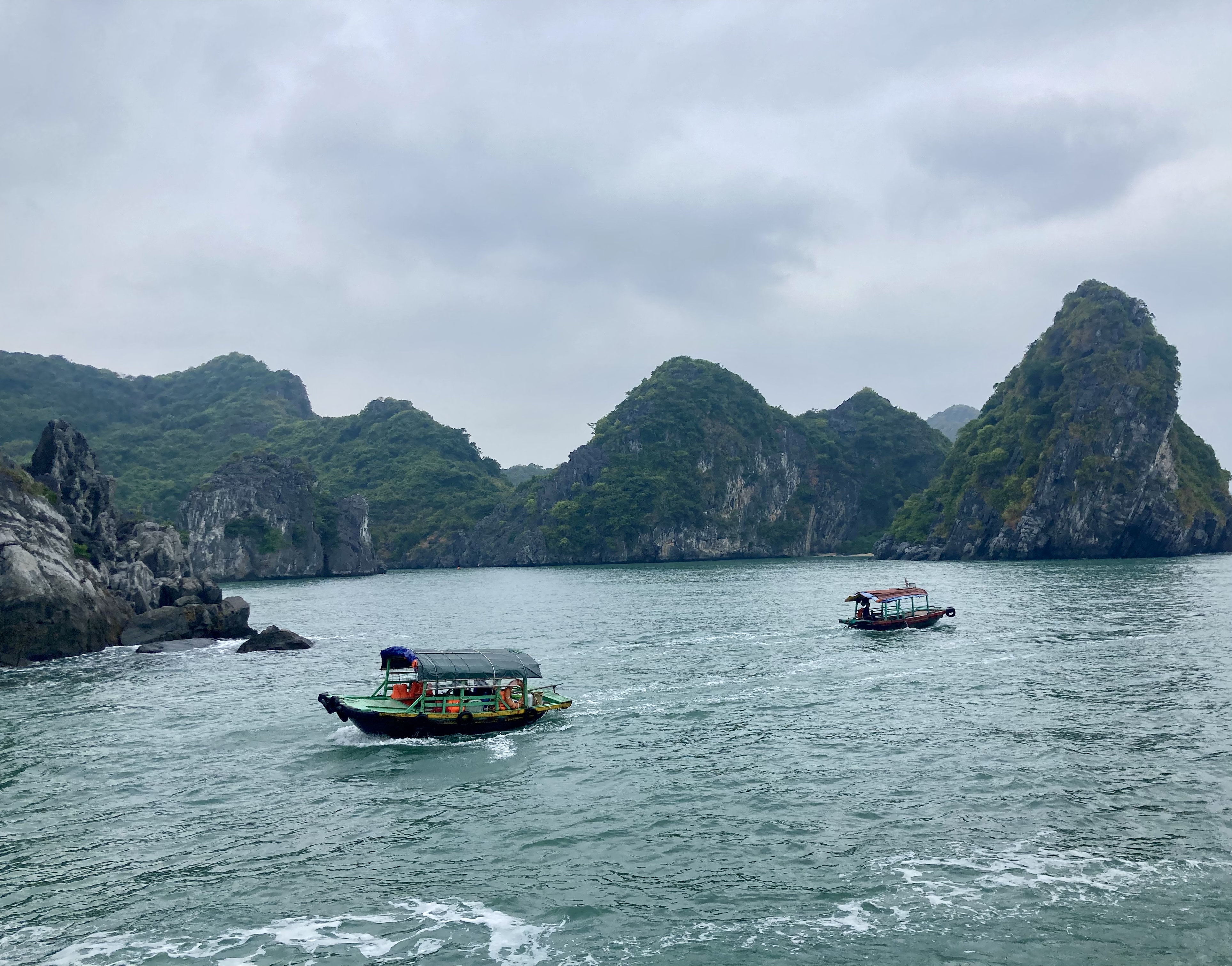 Boats moving through Ha Long Bay between limestone islands
