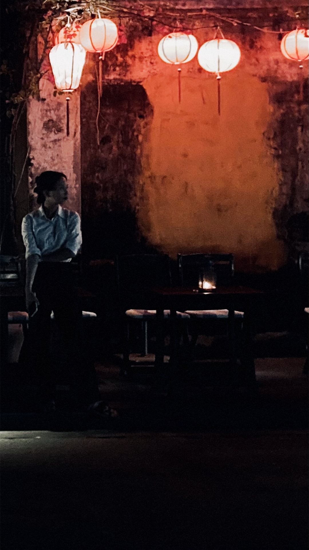 A person sitting under lanterns in Hoi An at night